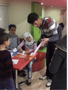 17-year-old Yaseen Hemzawi speaks at his first community-led social event in Syria, surrounded by youth participants.